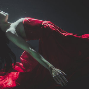 Eine Frau scheint sich unter Wasser zu entspannen. Suggeriert das Eintauchen in eine Trance.